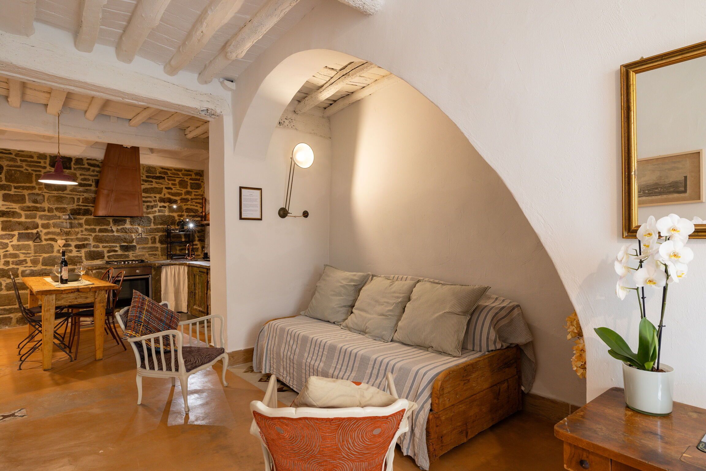 Una habitación acogedora con una cama, una mesa de comedor con sillas, una zona de cocina y un techo de madera.