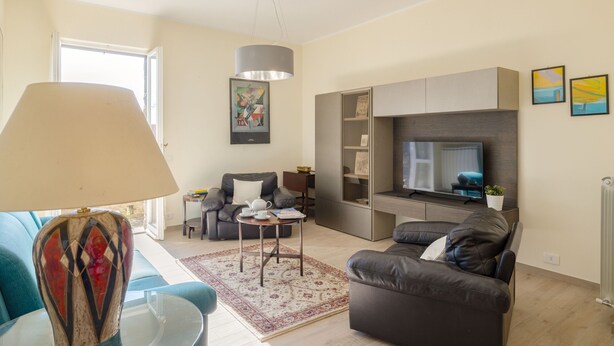 A modern living room with a sofa, a coffee table, a TV, and a lamp. - Casa Maria (Cortona)