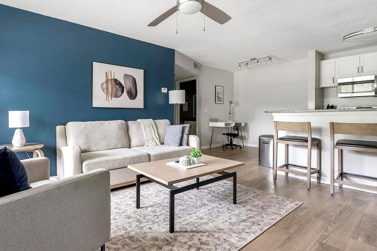 A modern living room with a sofa, coffee table, and a dining area with a bar.