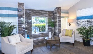 A modern living room with a large window, two sofas, a coffee table, and decorative plants. - Landing Apartments Fort Myers Near Pine Manor (Fort Myers)