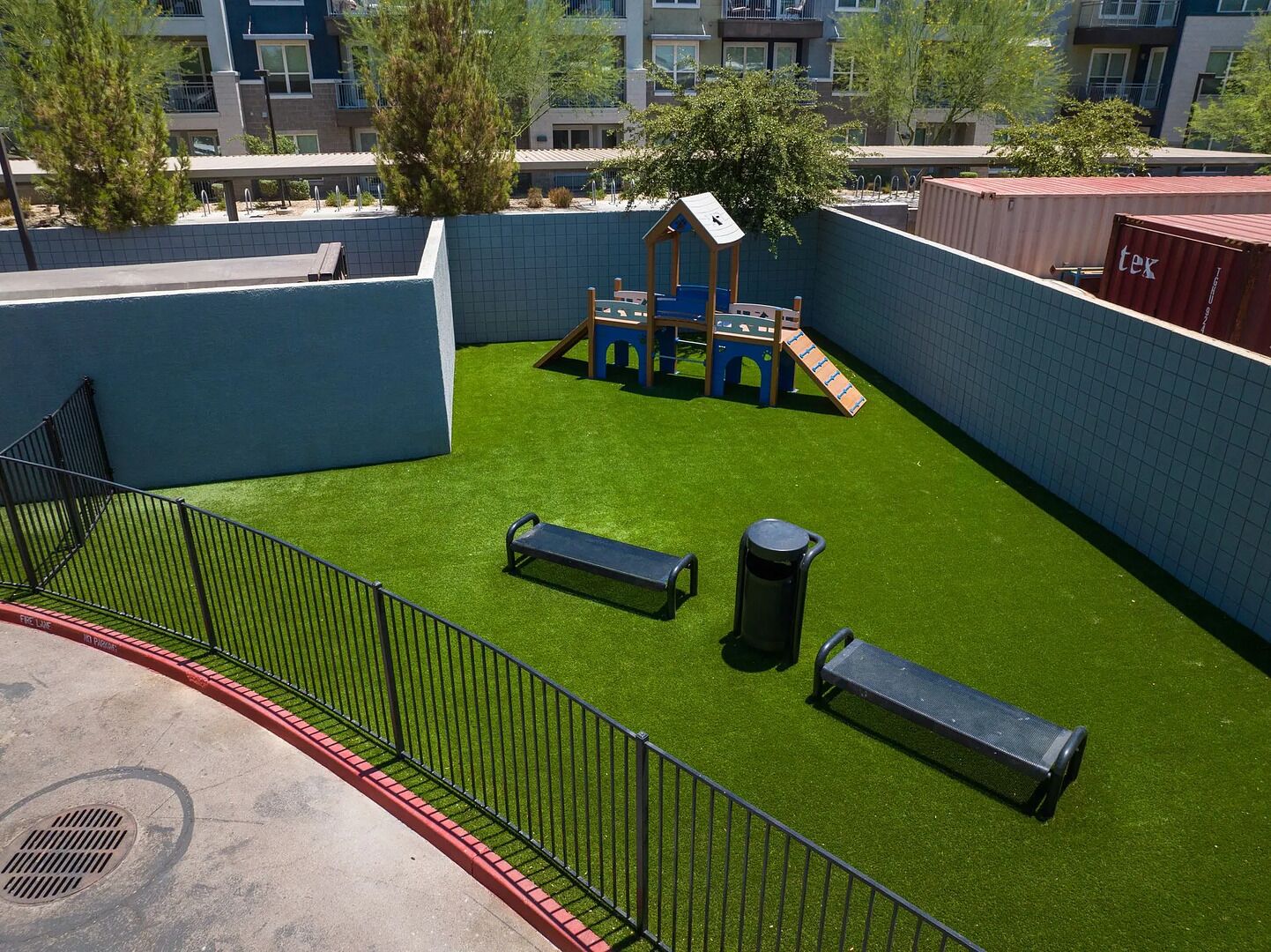Un espace de jeux sur le toit, avec une surface en gazon synthétique, des structures de jeu et des bancs.
