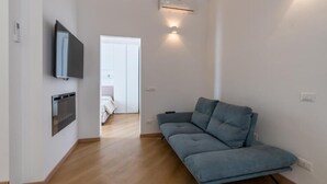 Uma sala de estar moderna com um sofá, uma TV na parede e um ar condicionado.