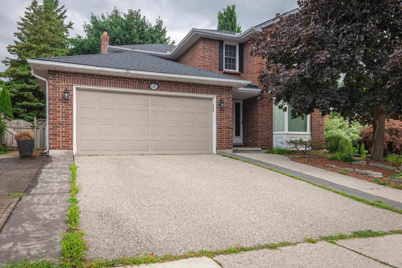A residential house with a garage, brick exterior, and a well-maintained lawn.