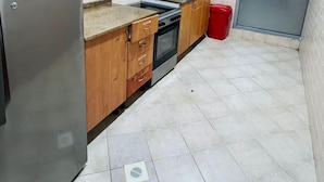 A compact kitchen with wooden cabinets, a stainless steel refrigerator, a stove, and a microwave. - Lavish Partition Room in Tecom (Dubai)