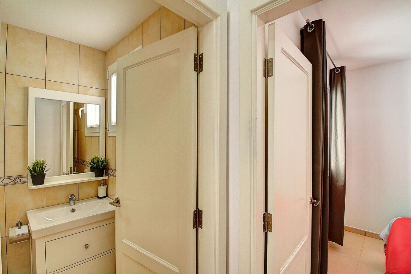 A bathroom with a sink, mirror, and two potted plants.