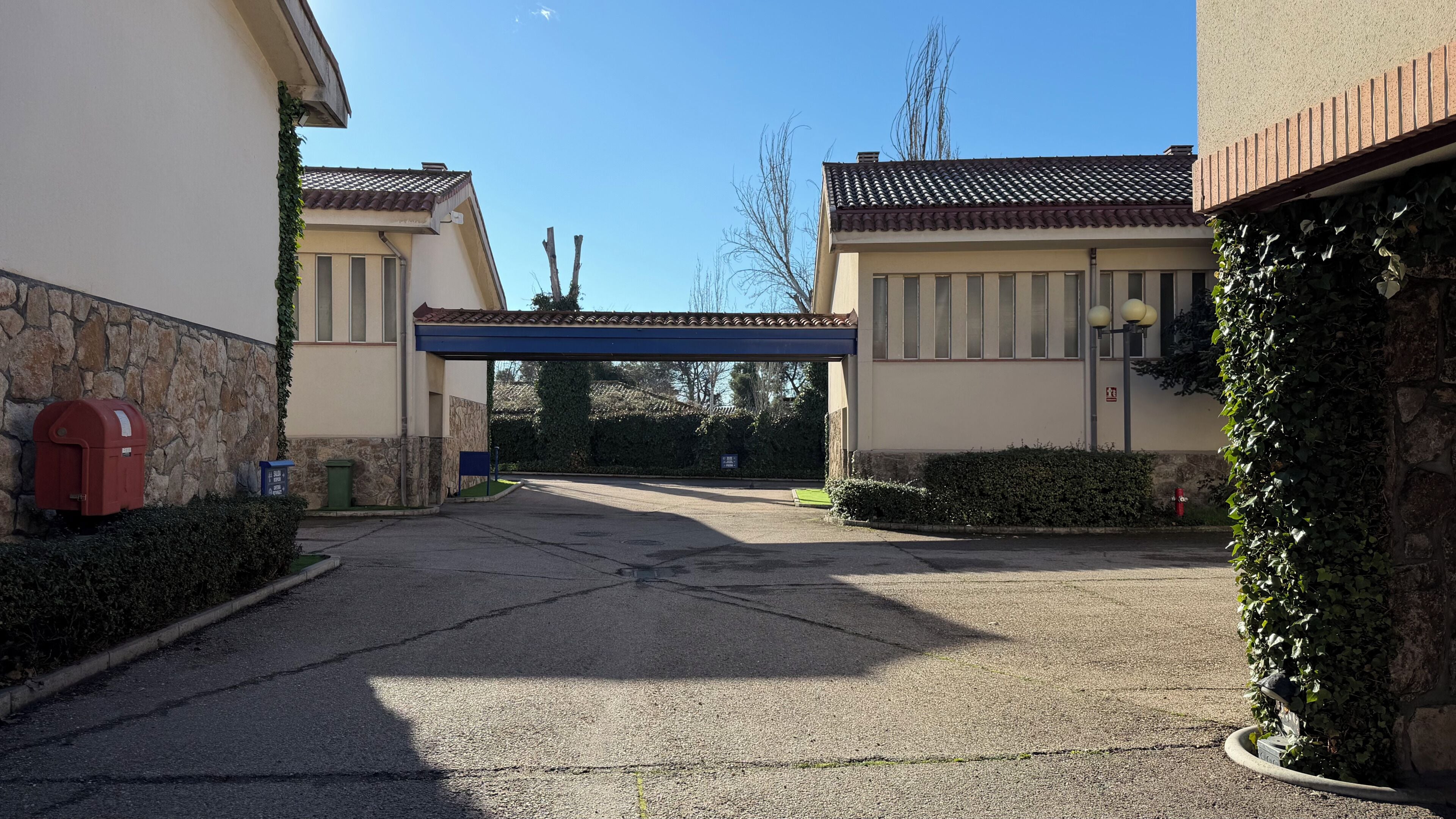 A parking area with a covered entrance, stone walls, and a mailbox.