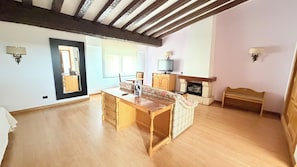 A spacious living room with a wooden floor, a sofa, a TV, and a fireplace.