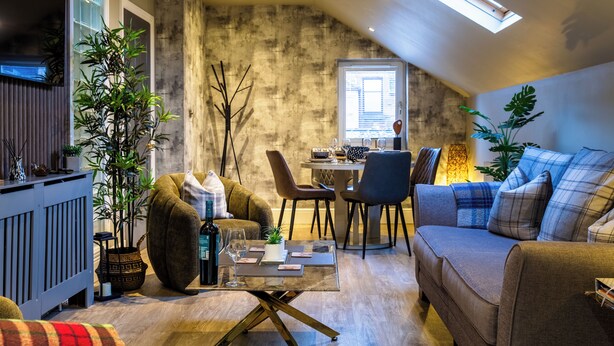 A cozy loft-style living space with a dining area, a sofa, and a coffee table. - Luxury apartment & terrace view over river & easy access to City Centre & Castle (Inverness)