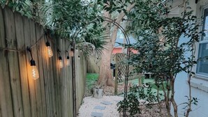 Un sendero bordeado de piedras para pisar que lleva a una cerca de madera con luces de cuerda.