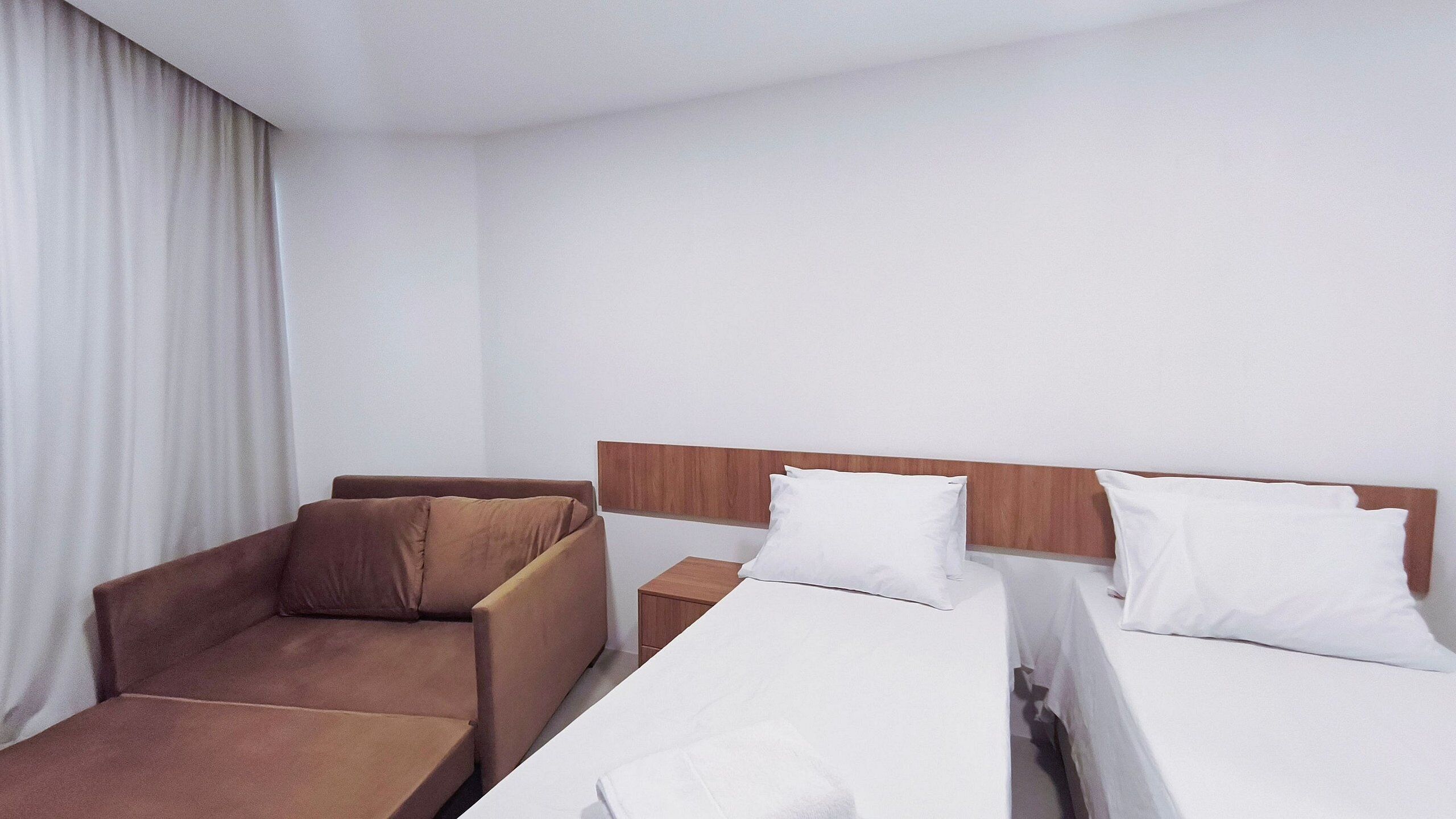 A hotel room with a bed, a chair, and a nightstand.