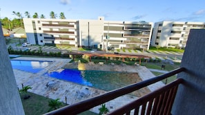 A modern hotel with a swimming pool, outdoor seating, and a view of the surrounding buildings.