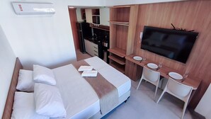 A hotel room with a bed, a TV, a kitchenette, and a small bathroom. - Atlântico Carneiros - Beira-Mar (Tamandaré)
