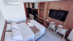 A compact hotel room with a bed, a TV, a small kitchenette, and a bathroom. - Atlântico Carneiros - Beira-Mar (Tamandaré)