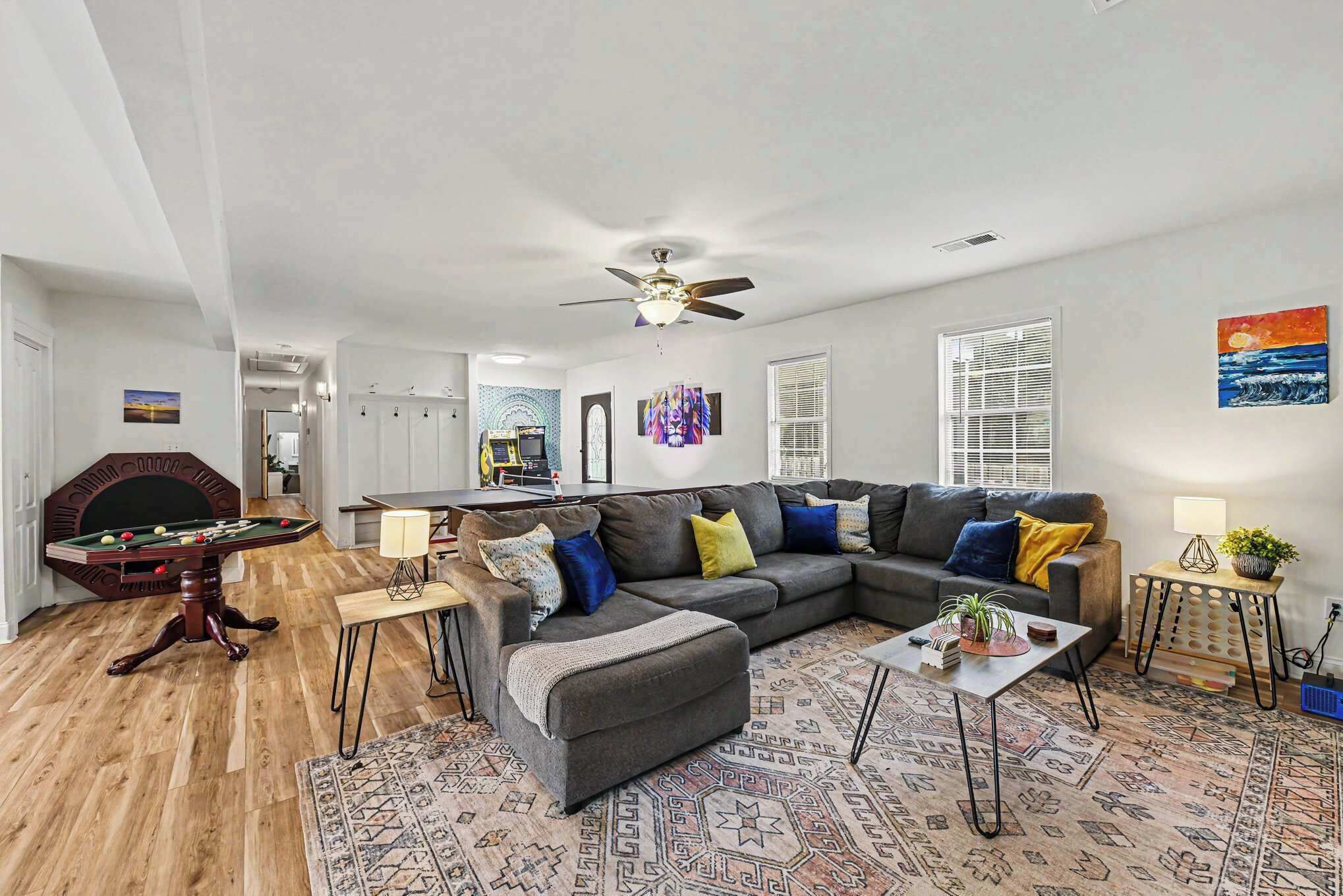 A living room with a pool table, a sofa, a coffee table, and a ceiling fan.