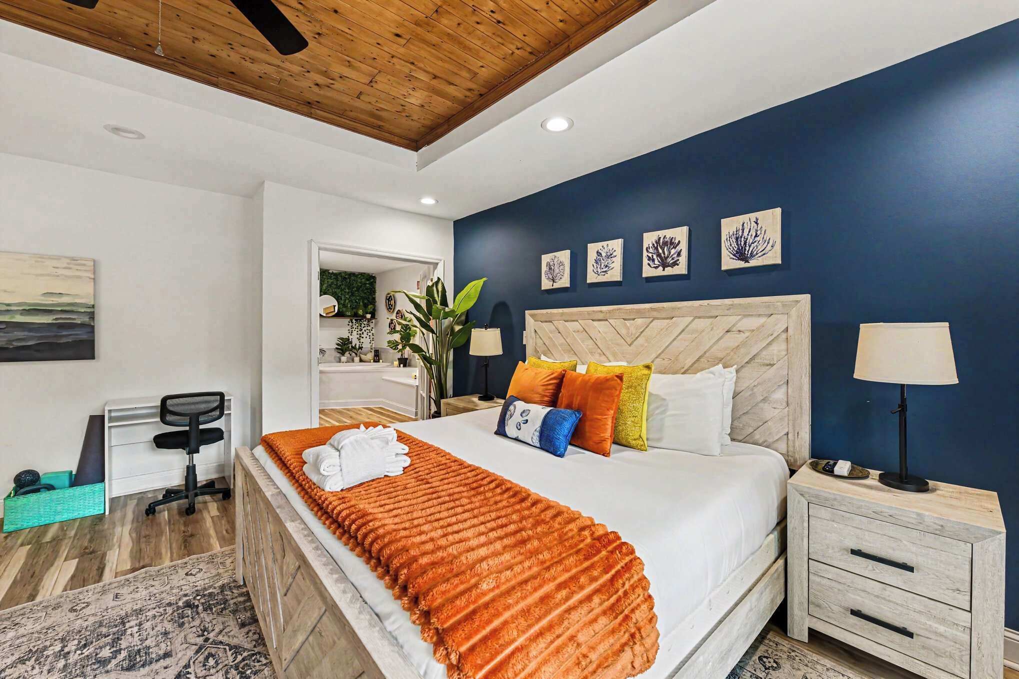 A bedroom with a bed, nightstands, a desk, and a chair.