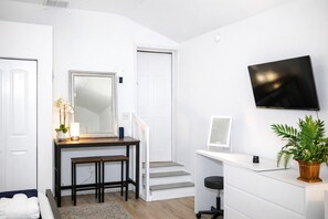 Una habitación moderna con escritorio, silla y televisión instalada en la pared.