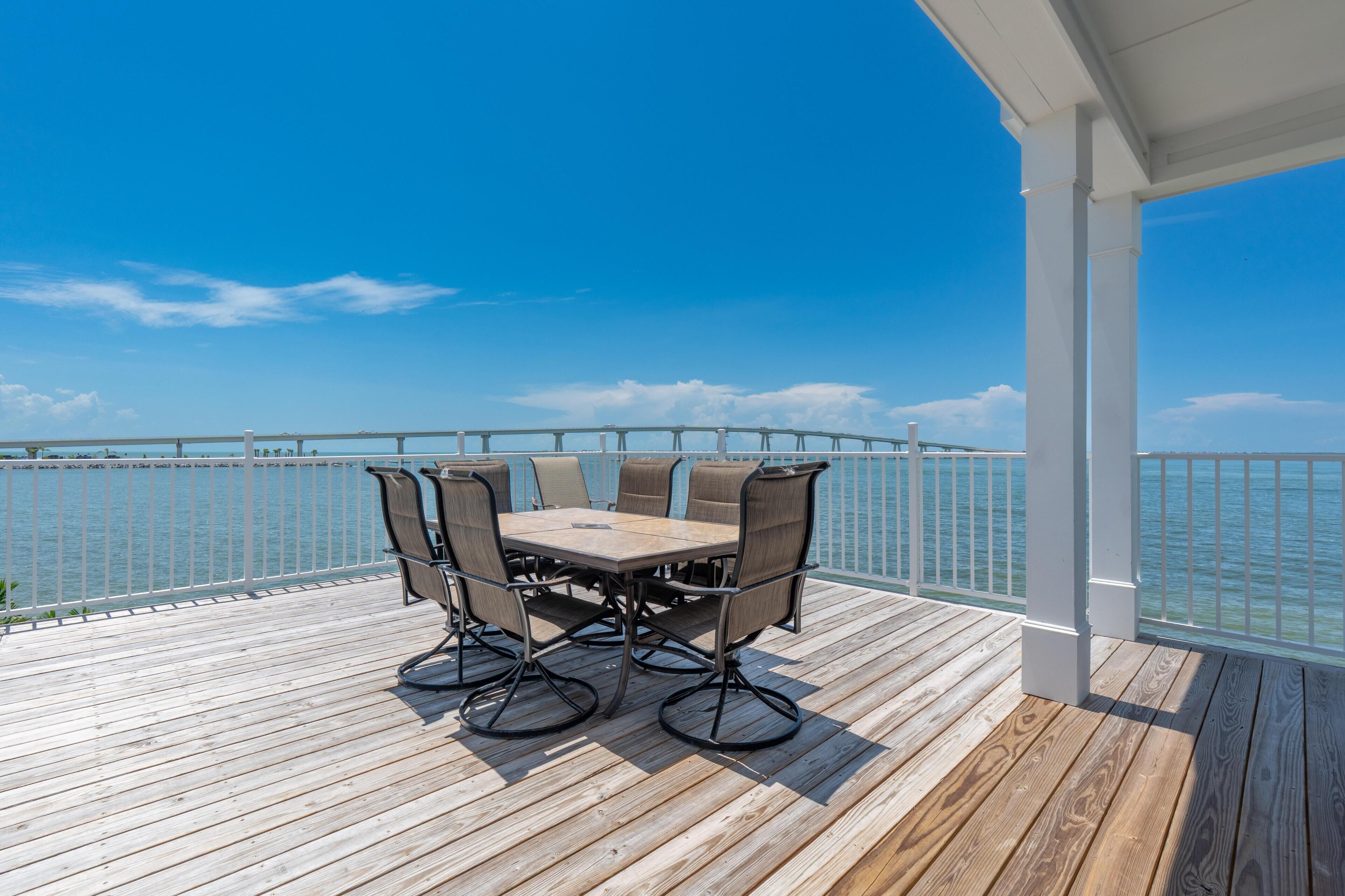 A wooden deck with a table and chairs, overlooking a body of water.