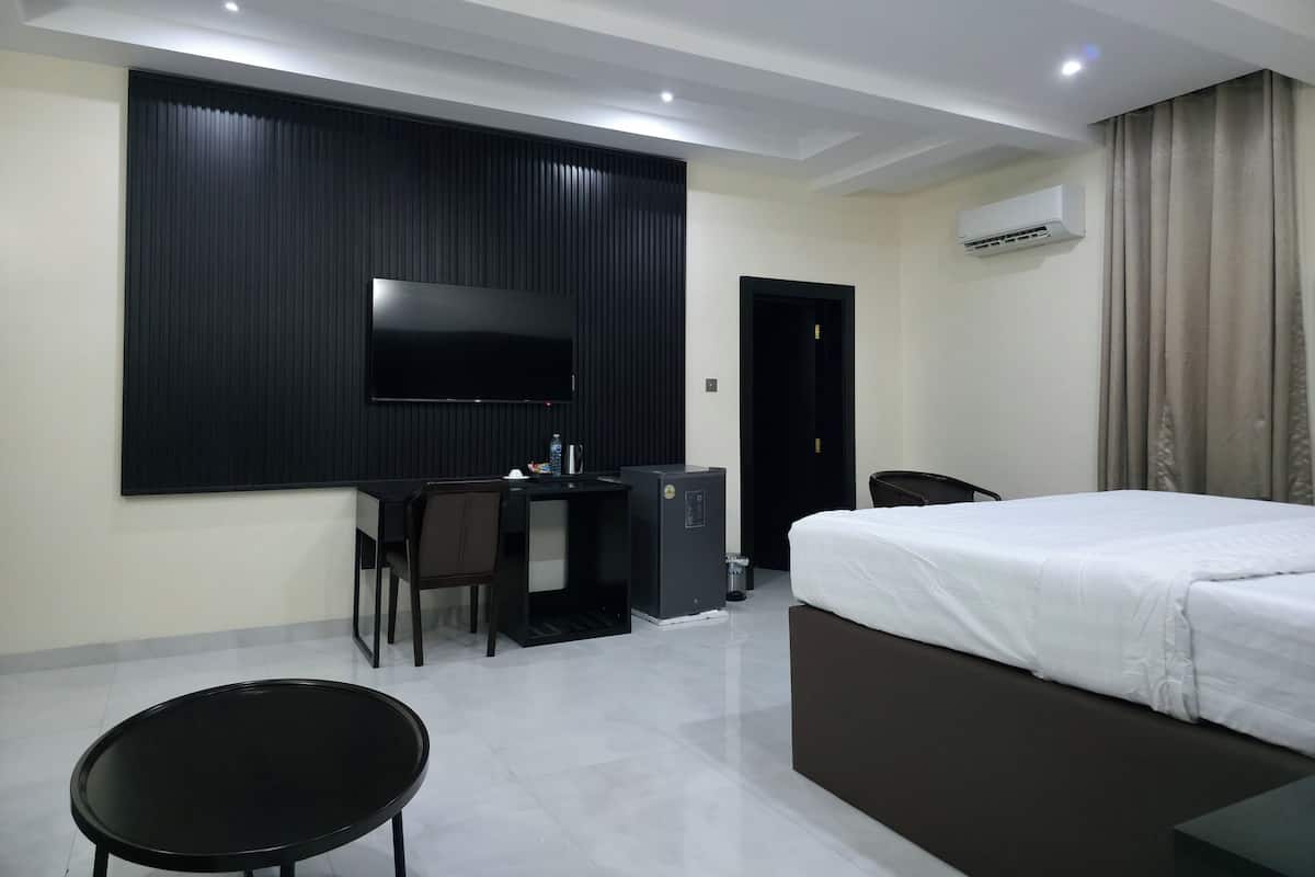 Une chambre d’hôtel moderne équipée d’un lit, d’un bureau, d’une chaise et d’un téléviseur fixé au mur.