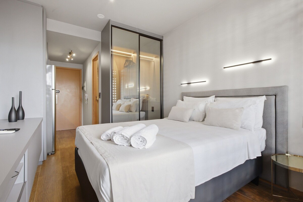 Ein stilvolles Hotelzimmer mit Bett, Nachttisch und einem Schrank mit Spiegel.