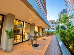 An outdoor patio area with seating and potted plants, overlooking a cityscape.