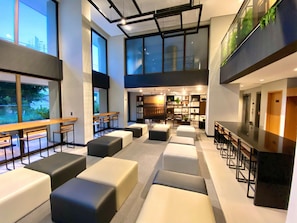 A modern interior with seating areas, a bar, and a view of the outdoors. - Unico Barra #1206 - Farol da Barra By Carpediem (Salvador)