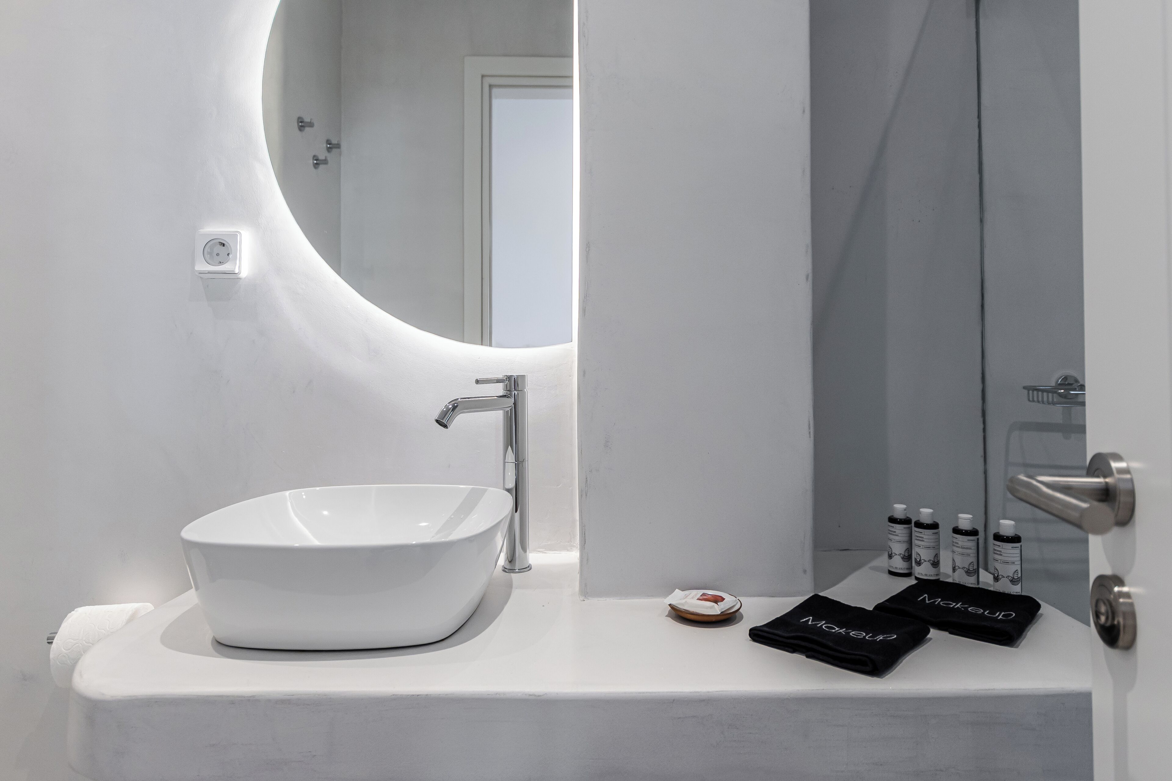 A modern bathroom with a white sink, a round mirror, and a glass shower enclosure.