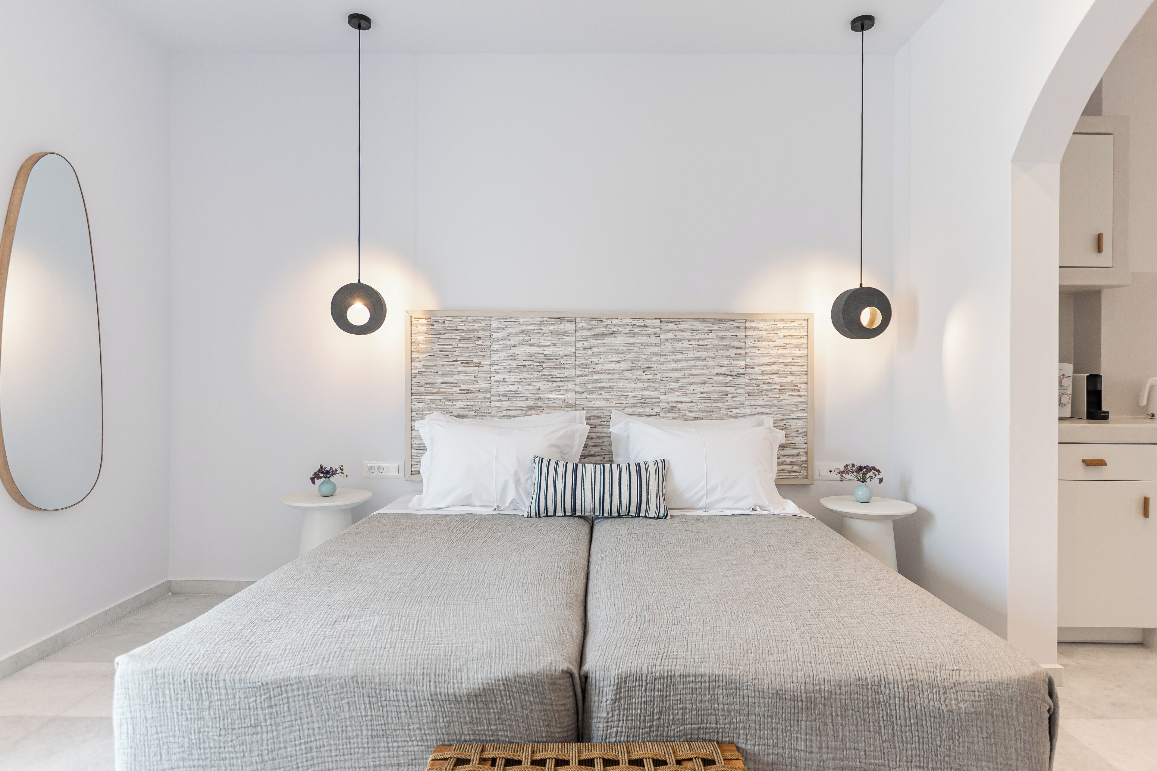 A modern bedroom with a large bed, two bedside tables, and a headboard with a textured design.