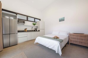 A compact bedroom with a bed, bedside table, and a small kitchenette area. - Pinilla Living Studio 2, Exclusive pool, secluded bedroom, private deck (Provincia de Guanacaste)