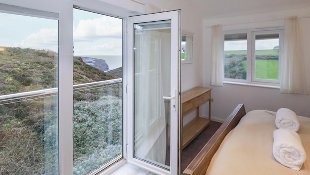 Un dormitorio con un ventanal grande, un banco de madera y una cama con toallas.