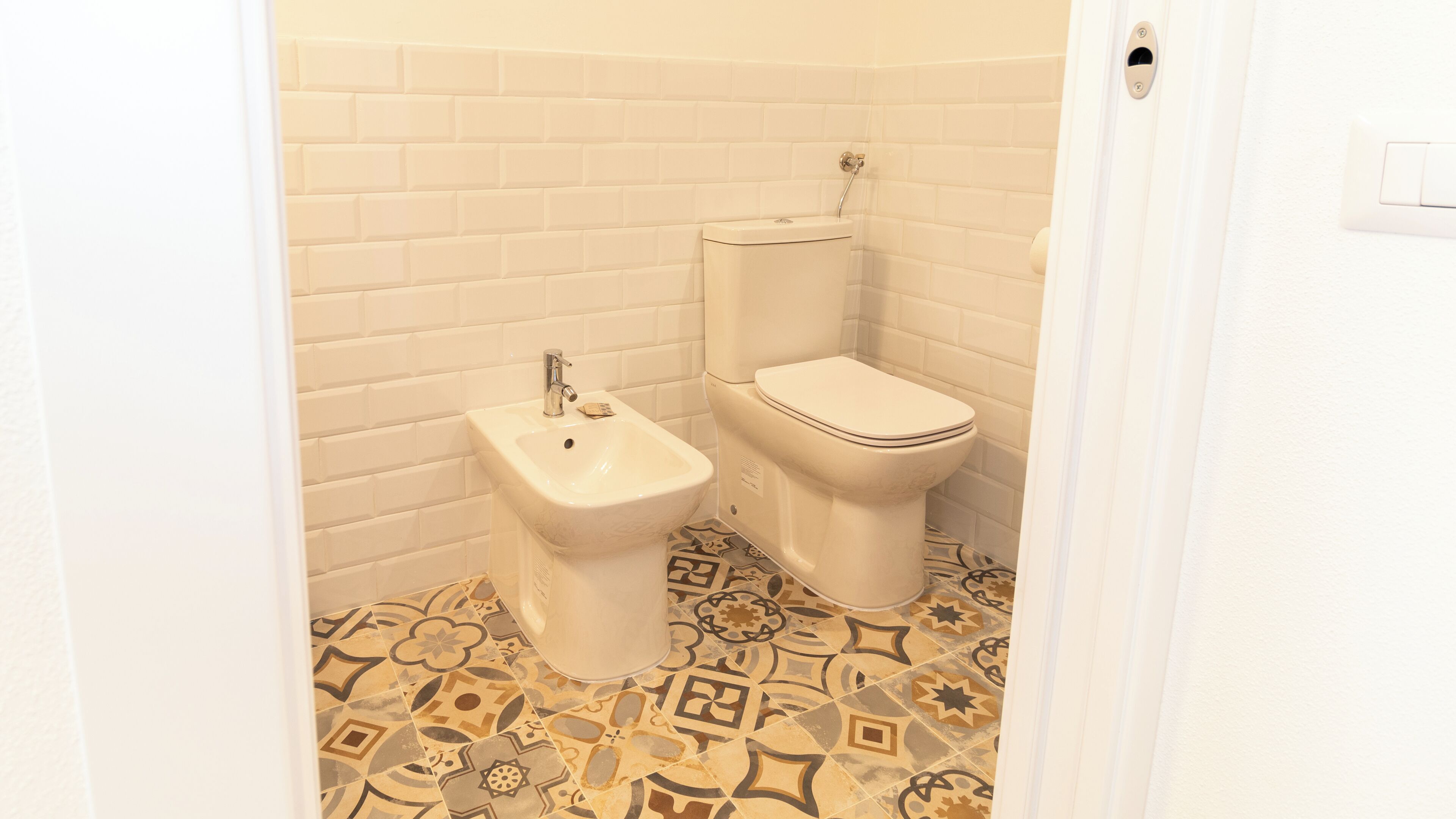 Ein Badezimmer mit einer Bidet, Toilette und Fliesenboden mit Muster.