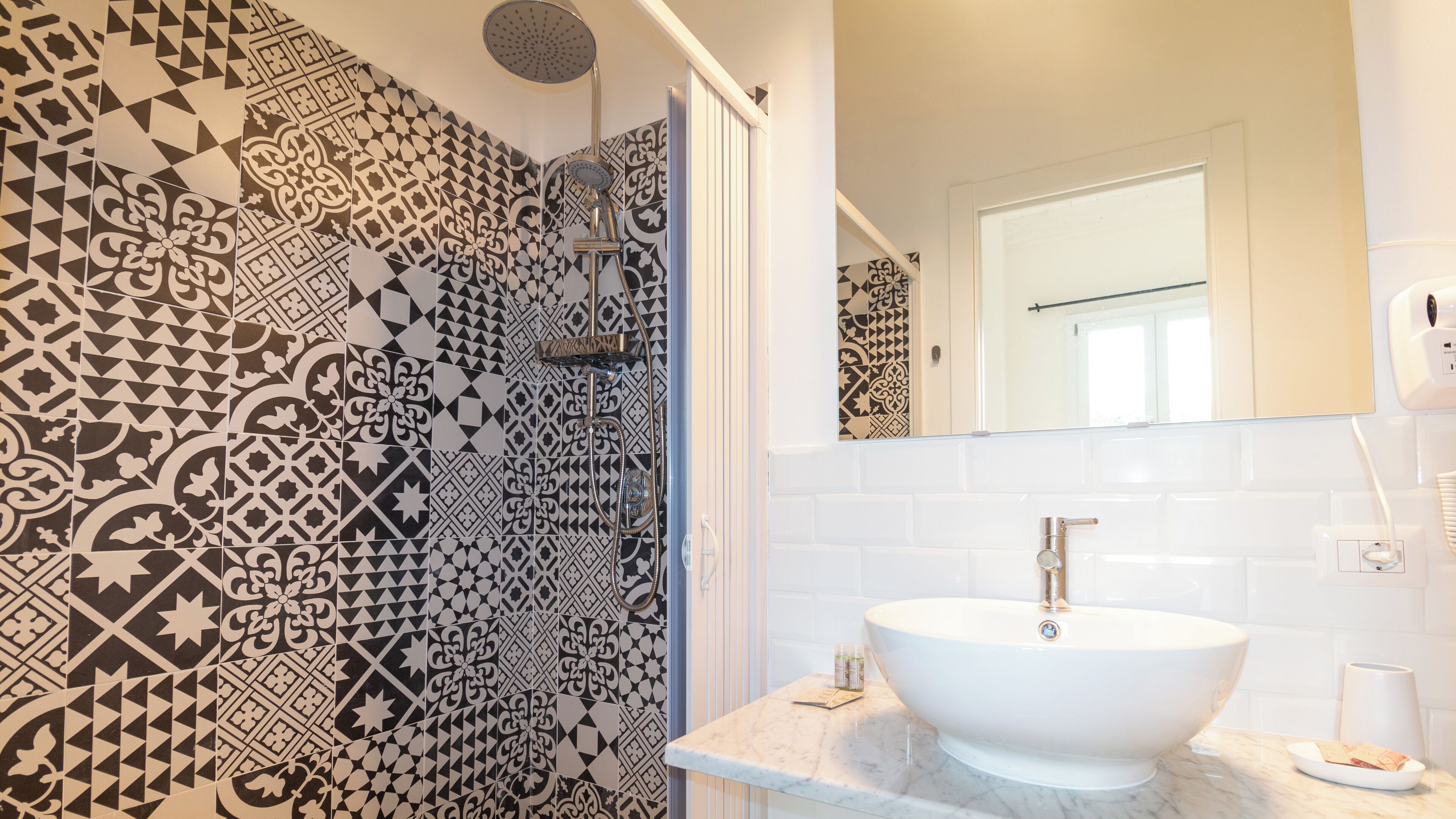 Une salle de bain avec des carreaux décorés, un lavabo blanc et un miroir.