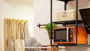 A modern kitchen with a built-in oven, a microwave, and a coffee machine. There is a shelf above the sink with a bread container and a plant. - Vatican City Deluxe (Rome)