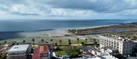 A coastal view with a beach, buildings, and a clear sky.