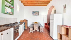 Een kleine keuken met een gasfornuis, oven en een houten eettafel met banken.