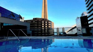 Ein modernes Gebäude mit einem Turm, einem Schwimmbad und blauem Himmel.