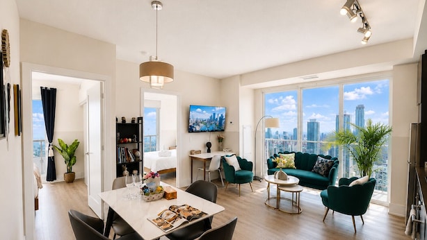 Ein modernes Wohnzimmer mit Essbereich, einer Couch, einem Fernseher und Blick auf die Stadt.