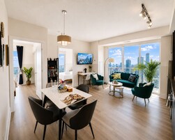 Een moderne woonkamer met een eetgedeelte, een bank, een televisie en uitzicht over de stad.