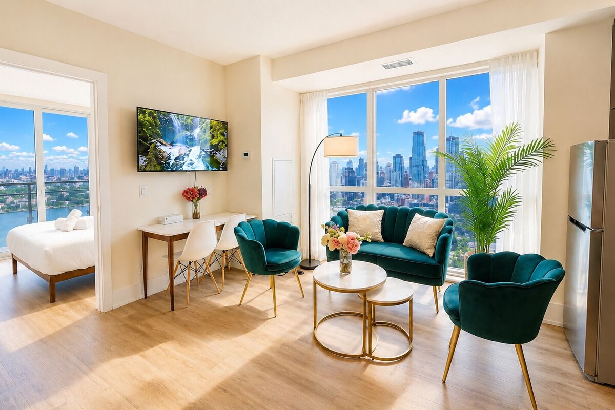 Una sala de estar moderna con vista a la ciudad, un sofá, sillas, una mesa de centro y un televisor.