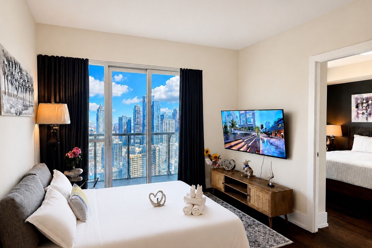 Una habitación de hotel con cama, televisión, vista a la ciudad, escritorio y mesita de noche.