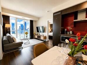 Una habitación de hotel moderna con sofá, mesa de comedor y zona de cocina.