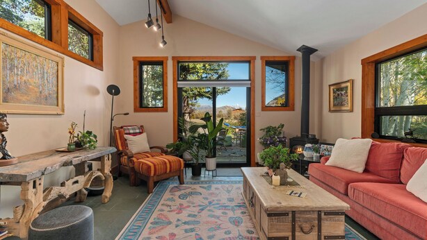 A cozy living room with a fireplace, large windows, and a rustic coffee table. - Luxury Teton Ski Getaway: Beautiful 4BR Home (Jackson)