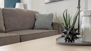 A modern living room with a grey sofa, patterned pillow, and a decorative plant on a wooden table. - Landing Apartments San Antonio near Baptist Neighborhood Hospital (San Antonio)