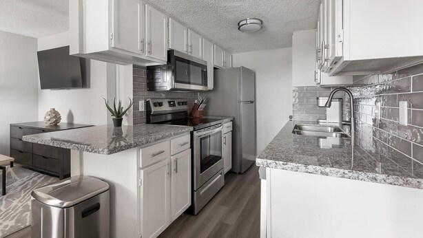 A modern kitchen with white cabinets, stainless steel appliances, and a granite countertop. - Landing Apartments San Antonio near Baptist Neighborhood Hospital (San Antonio)