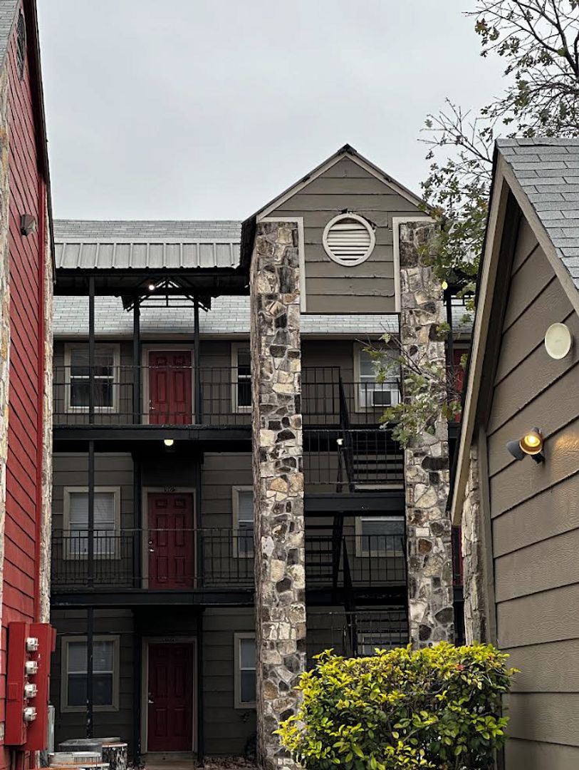 Un immeuble à plusieurs étages, doté d’une façade en pierre, de portes rouges et d’un porche abrité.