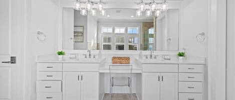 A modern bathroom with two sinks, a large mirror, and overhead lighting.