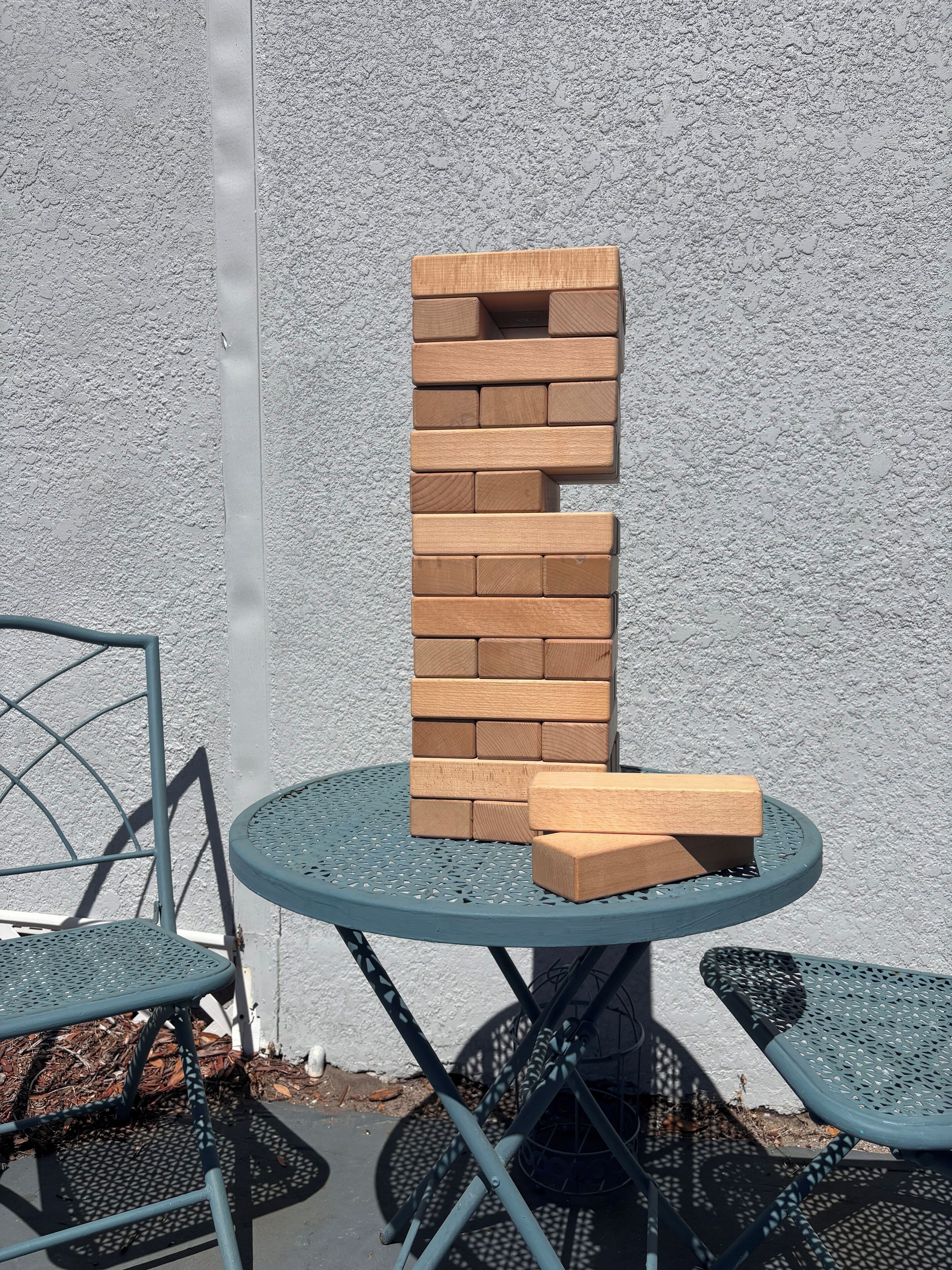 Une table ronde en métal, surmontée d’une structure en briques, entourée de chaises en métal.