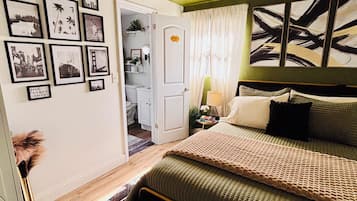 Une chambre à coucher avec un lit, une table de chevet, une lampe et un mur orné de tableaux.