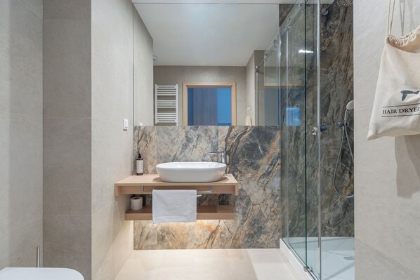 A modern bathroom with a marble sink, glass shower enclosure, and a towel hanging on a rack. - Hidden Coast Apartments - Premium Seaside Apartments with Pool, 2-Minute Walk to the Beach (Łukęcin)