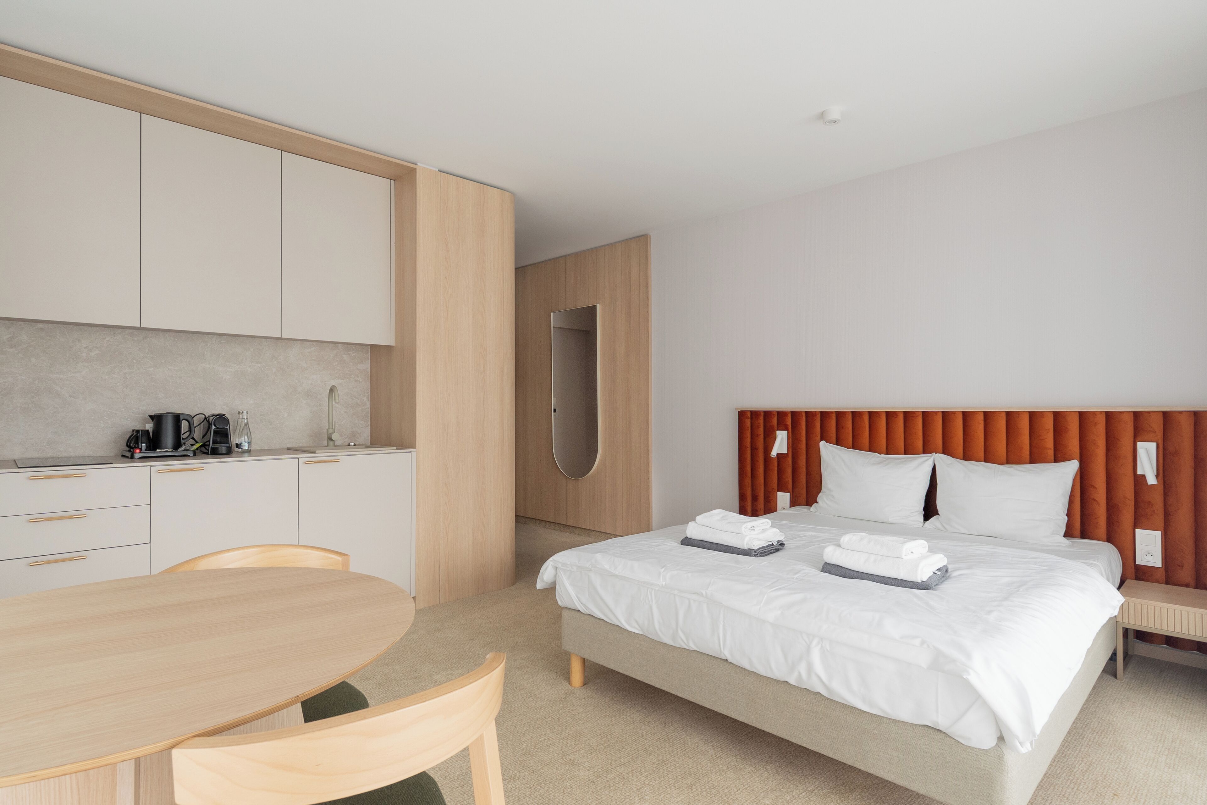 Een moderne hotelkamer met een bed, bureau en kitchenette.
