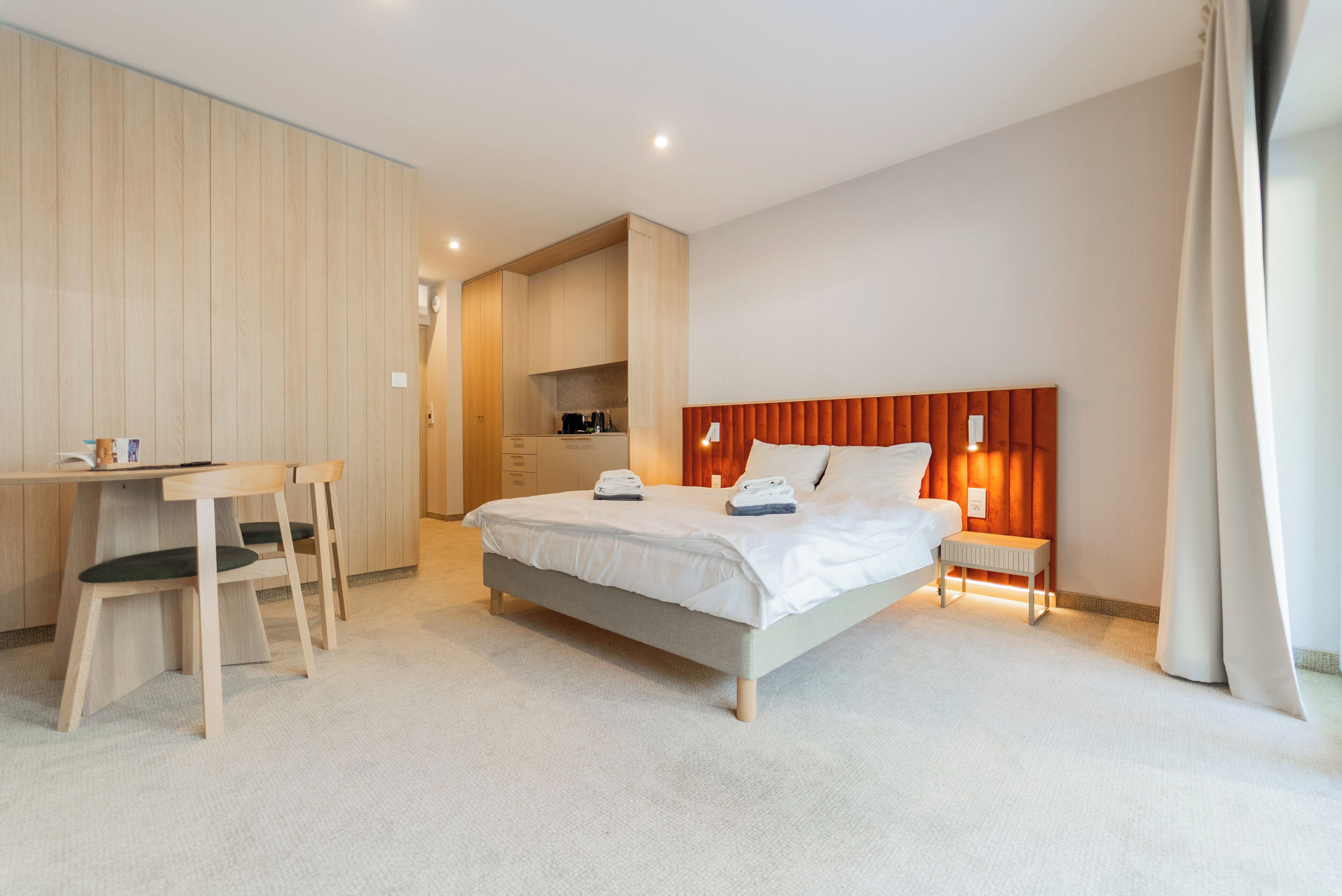 Una habitación de hotel moderna con una cama, una mesita de noche y un escritorio con sillas.